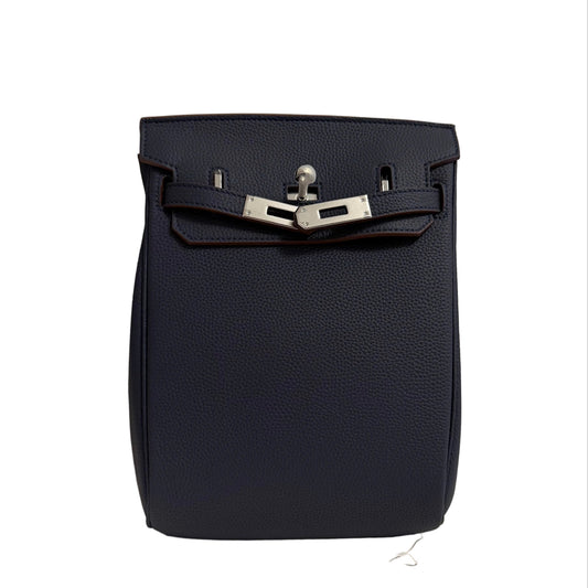 Navy blue leather bag with silver buckle on a neutral background