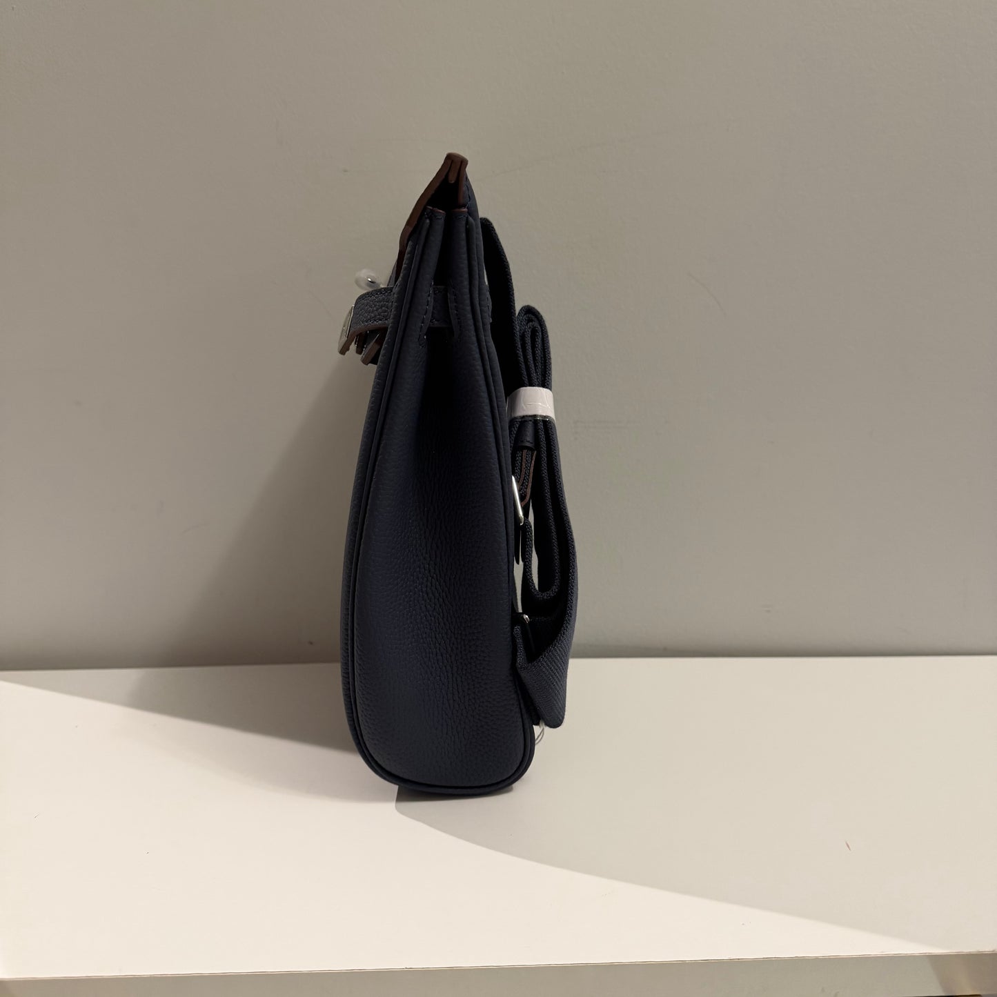 Black leather bag on a white surface with a neutral background