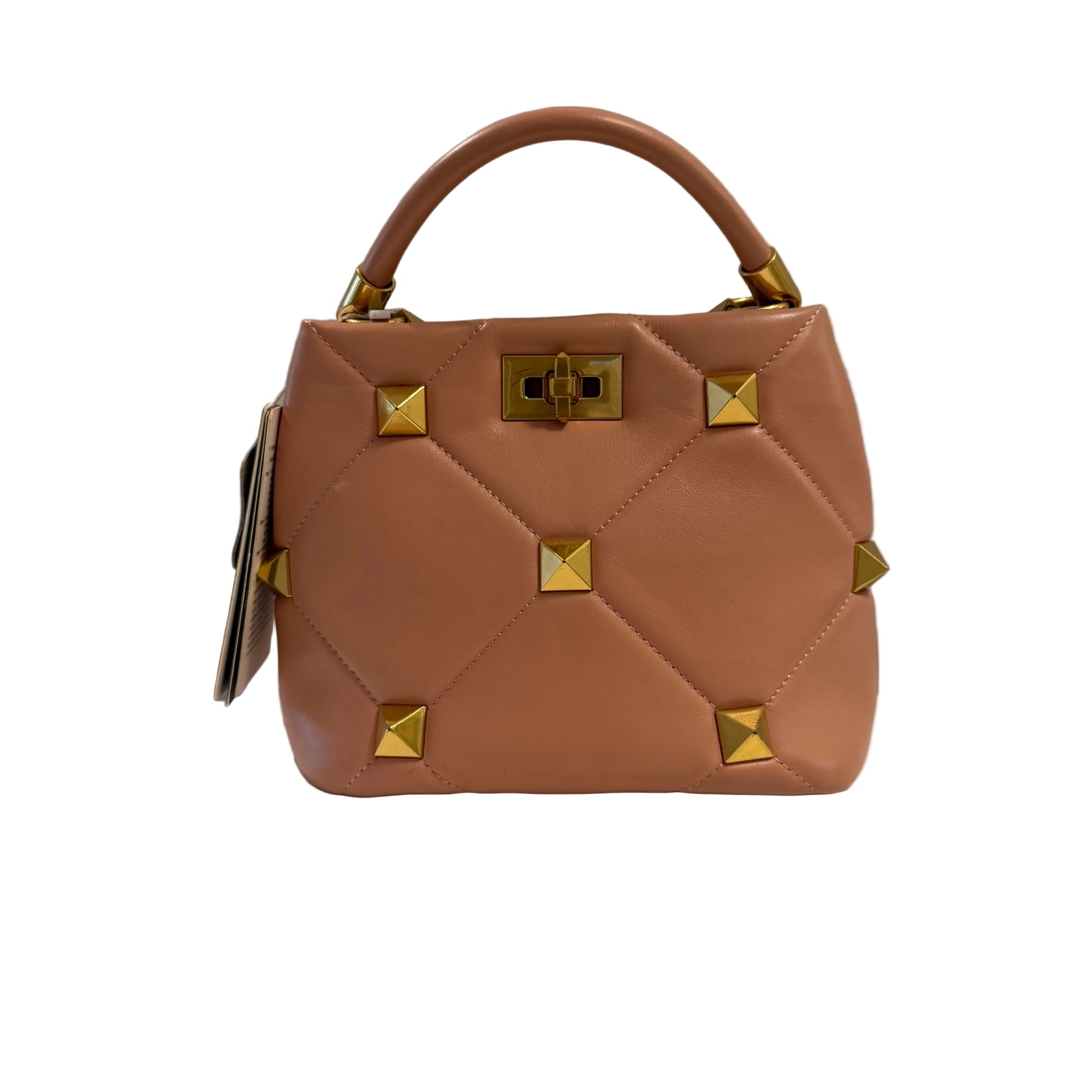 Brown handbag with gold studs on a white surface and gray background