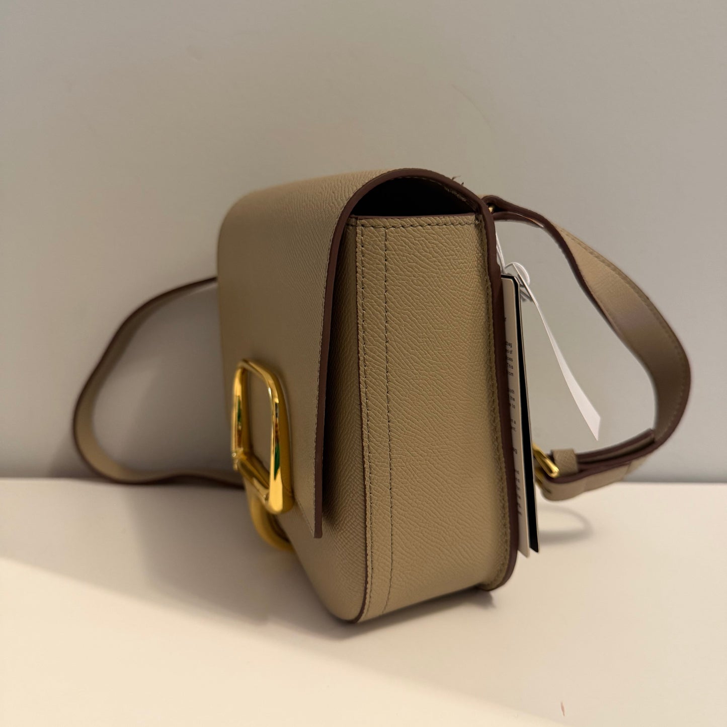 Beige handbag with gold clasp on a light gray background