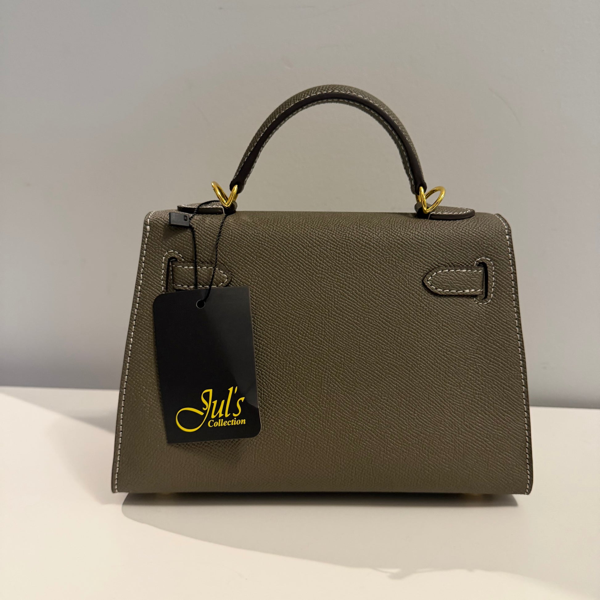 Brown handbag with a black tag on a light gray background