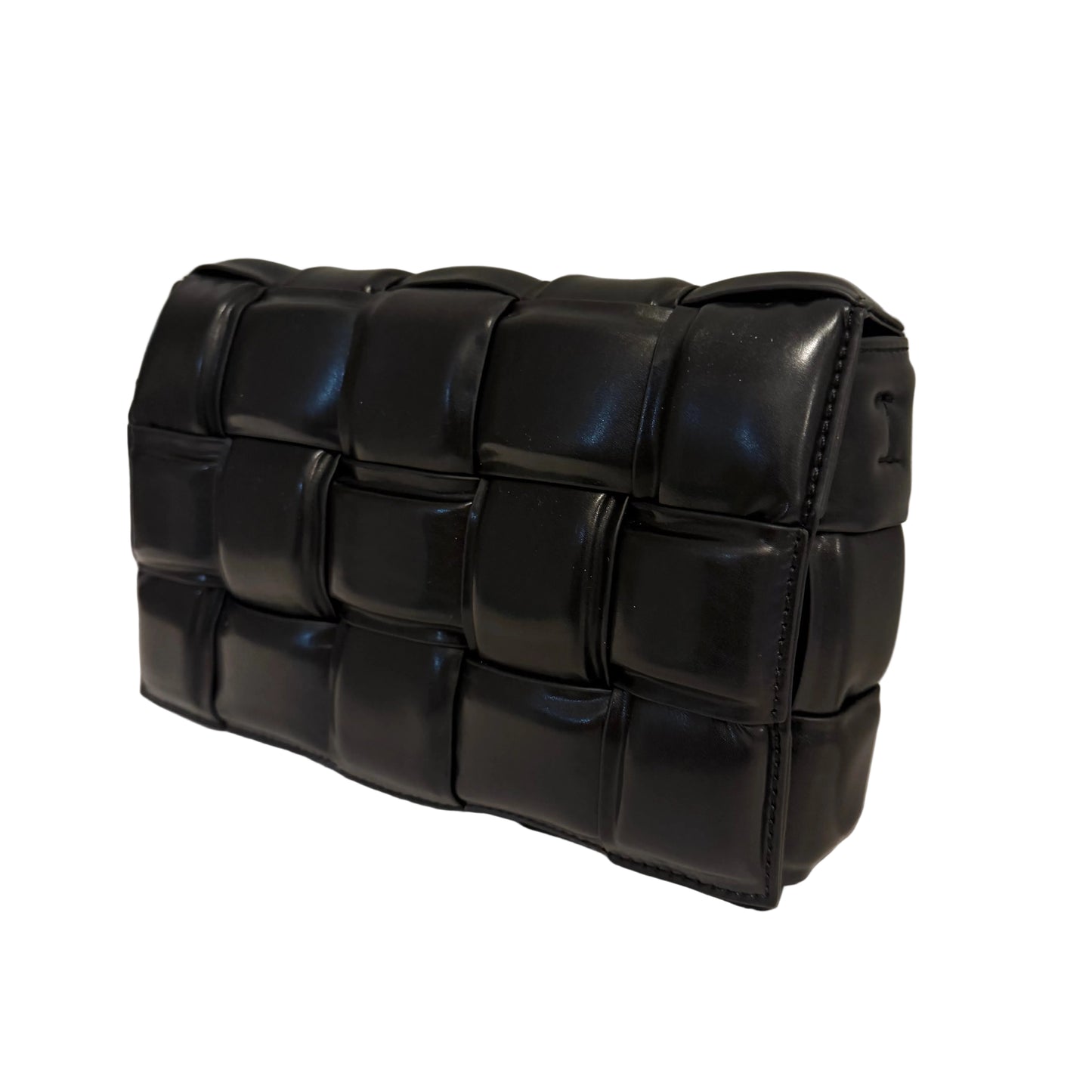 Black woven handbag on a light surface with a neutral background