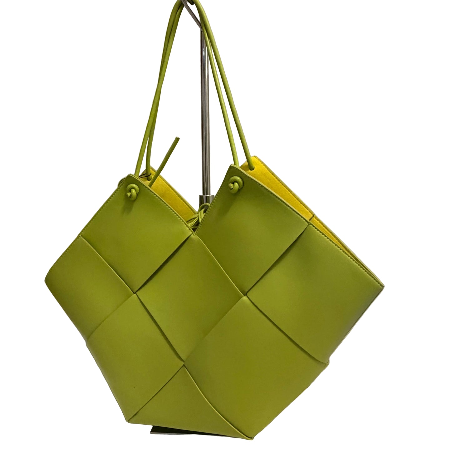 Green woven handbag on a white surface with a neutral background