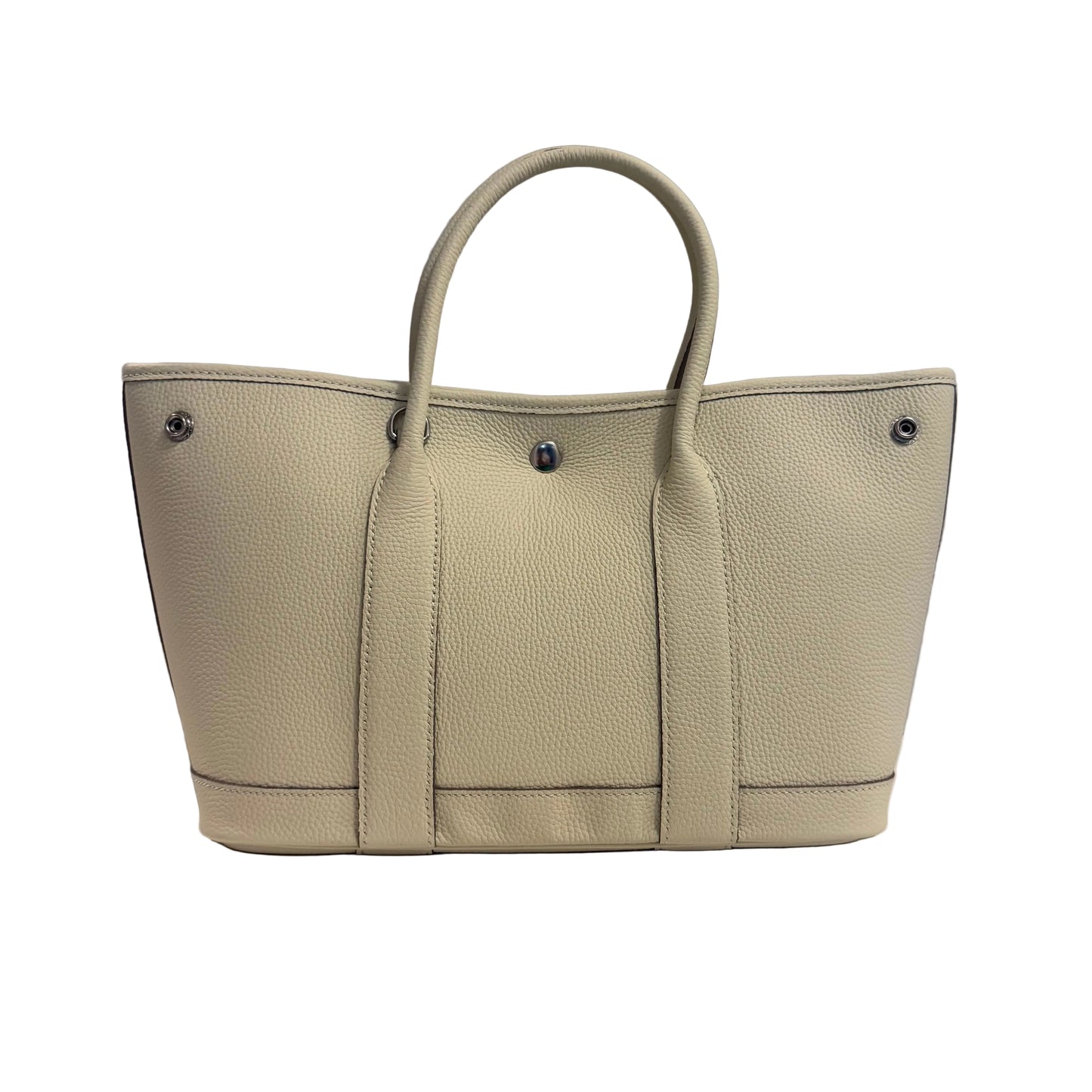 Beige handbag on a white surface with a gray background