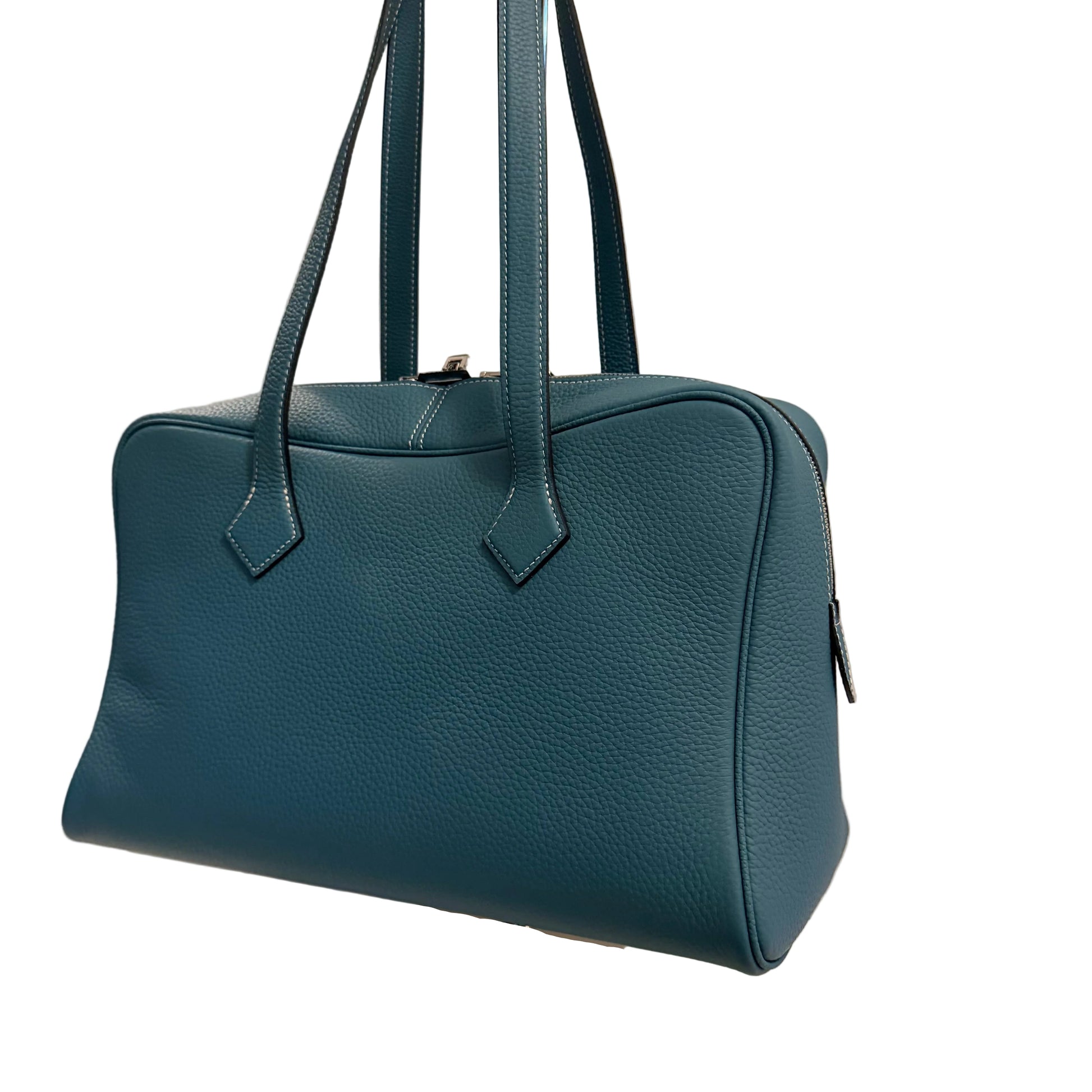 Blue handbag on a white stand with a neutral background