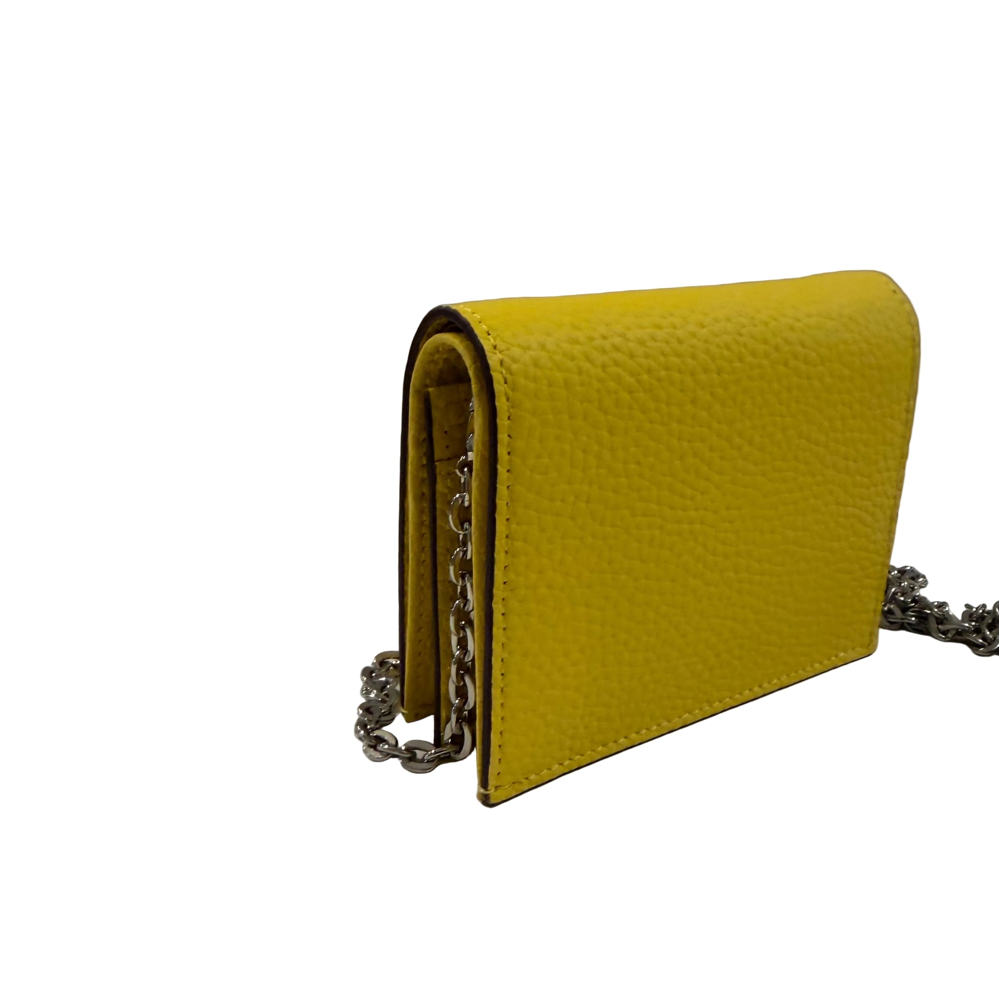 Yellow wallet with a chain detail on a white surface and gray background