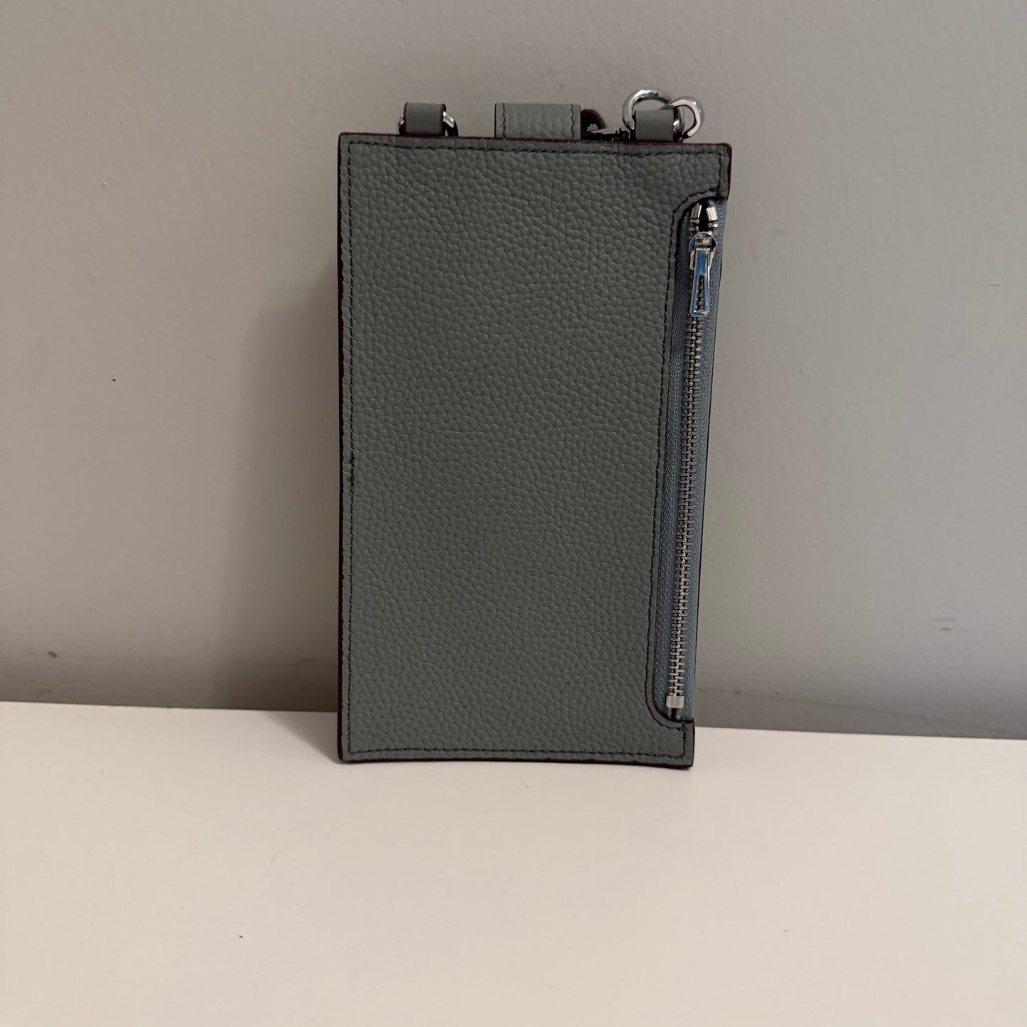 Dark gray leather pouch with zipper on a light gray background