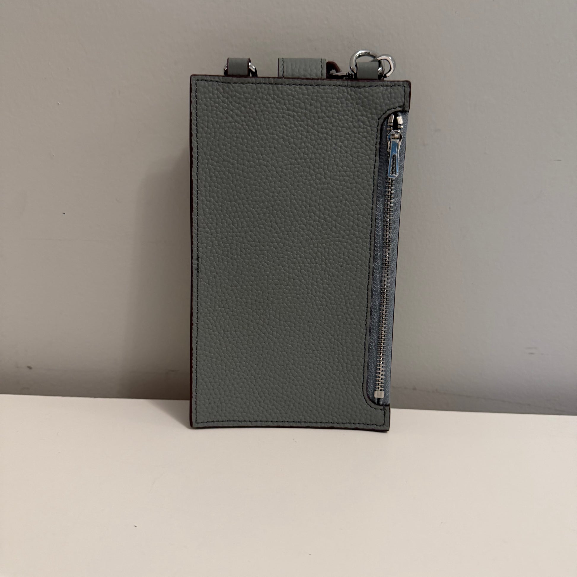 Dark gray leather pouch with zipper on a light gray background
