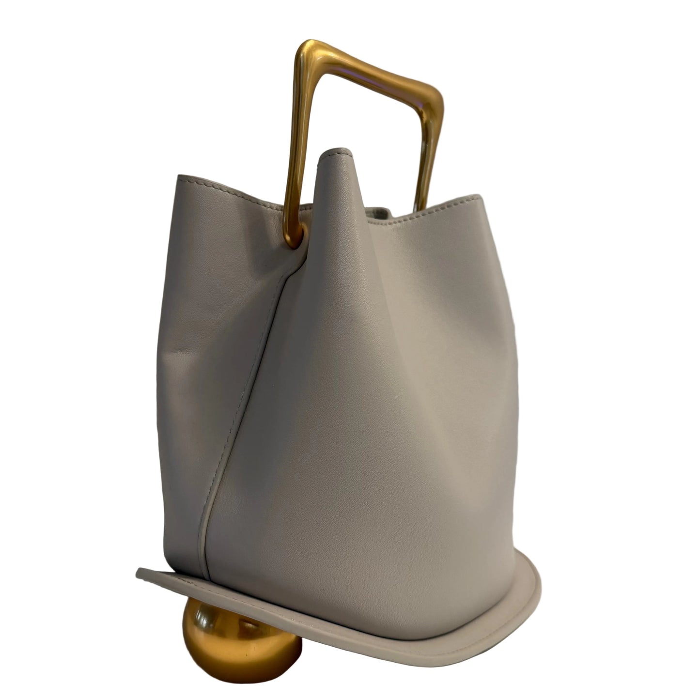 Gray handbag with a gold handle on a white surface with a gray background