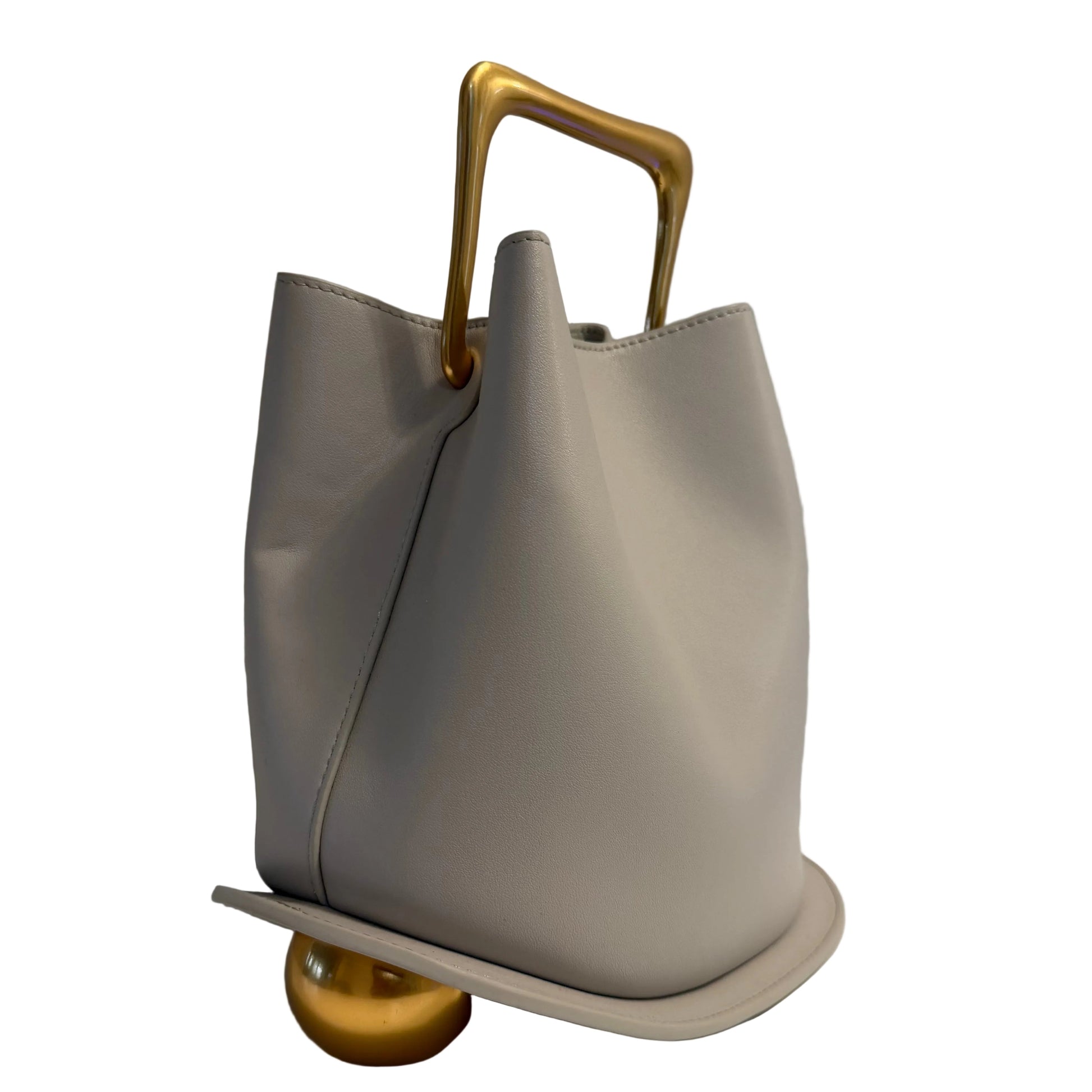 Gray handbag with a gold handle on a white surface with a gray background