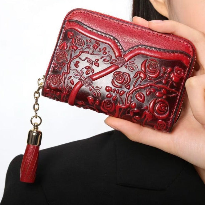 Red embroidered wallet with tassel held by a person against a white background
