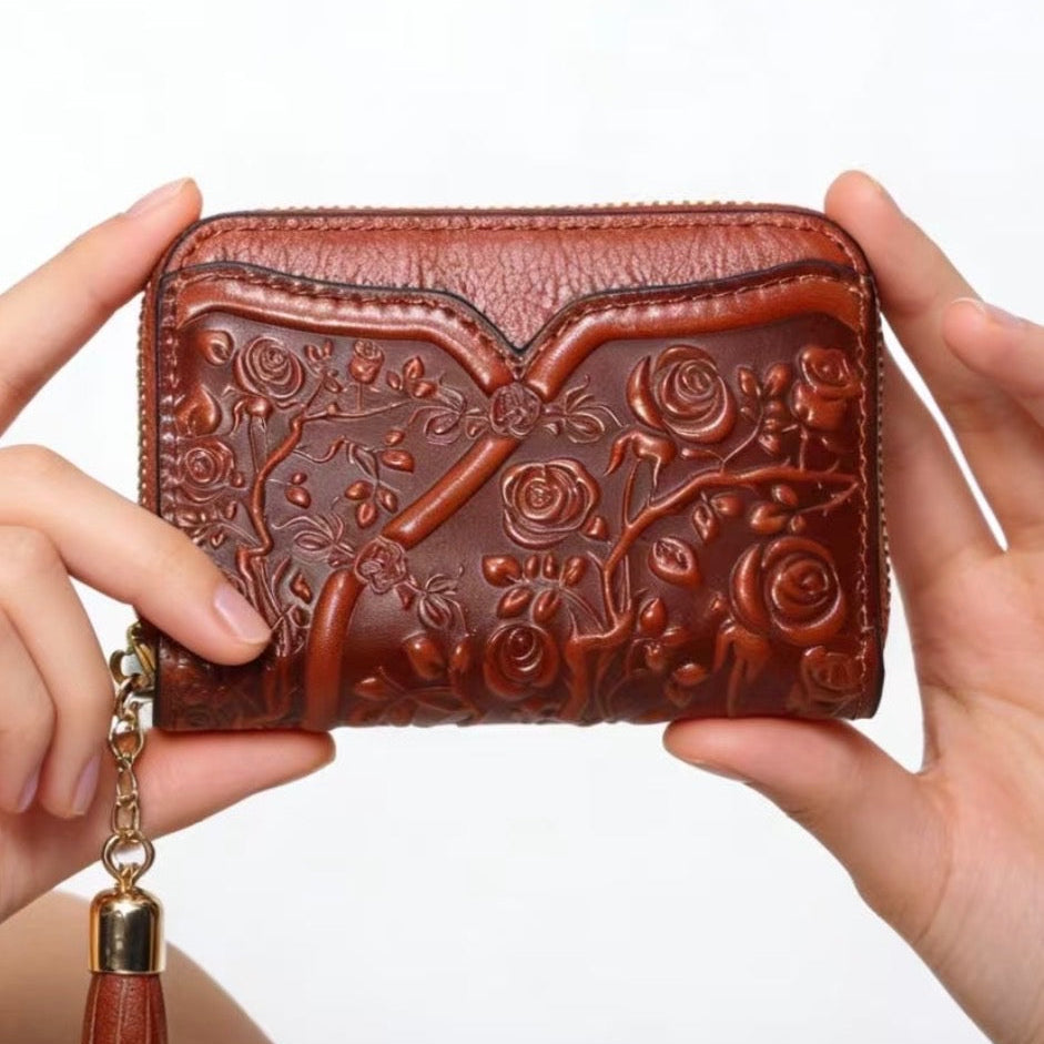 Brown embossed wallet with floral designs held by hands on a white background