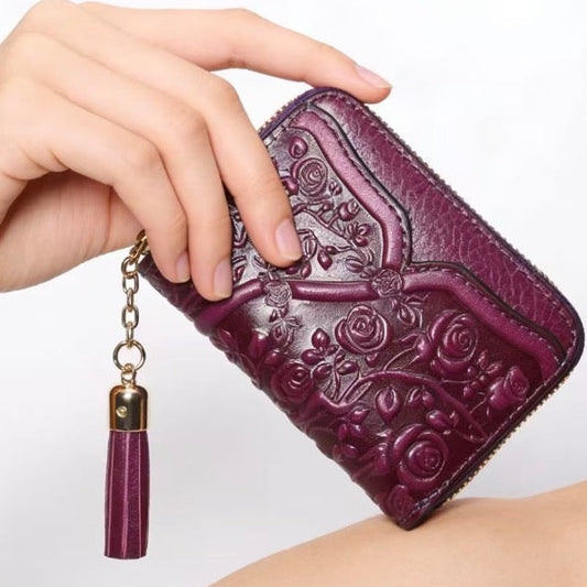Purple wallet with floral embossing and tassel held by a hand on a white background