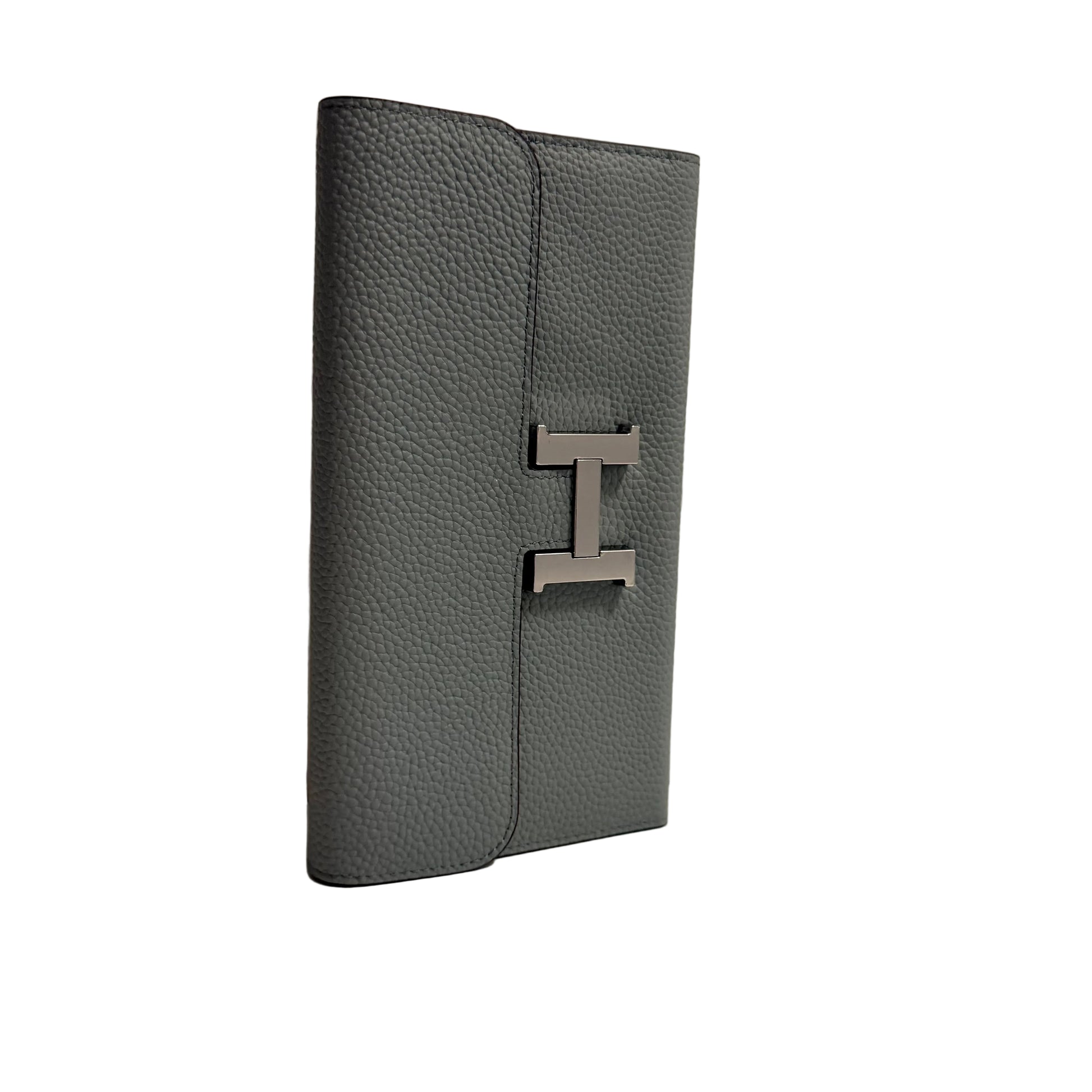 Gray leather wallet with a metal logo on a beige background