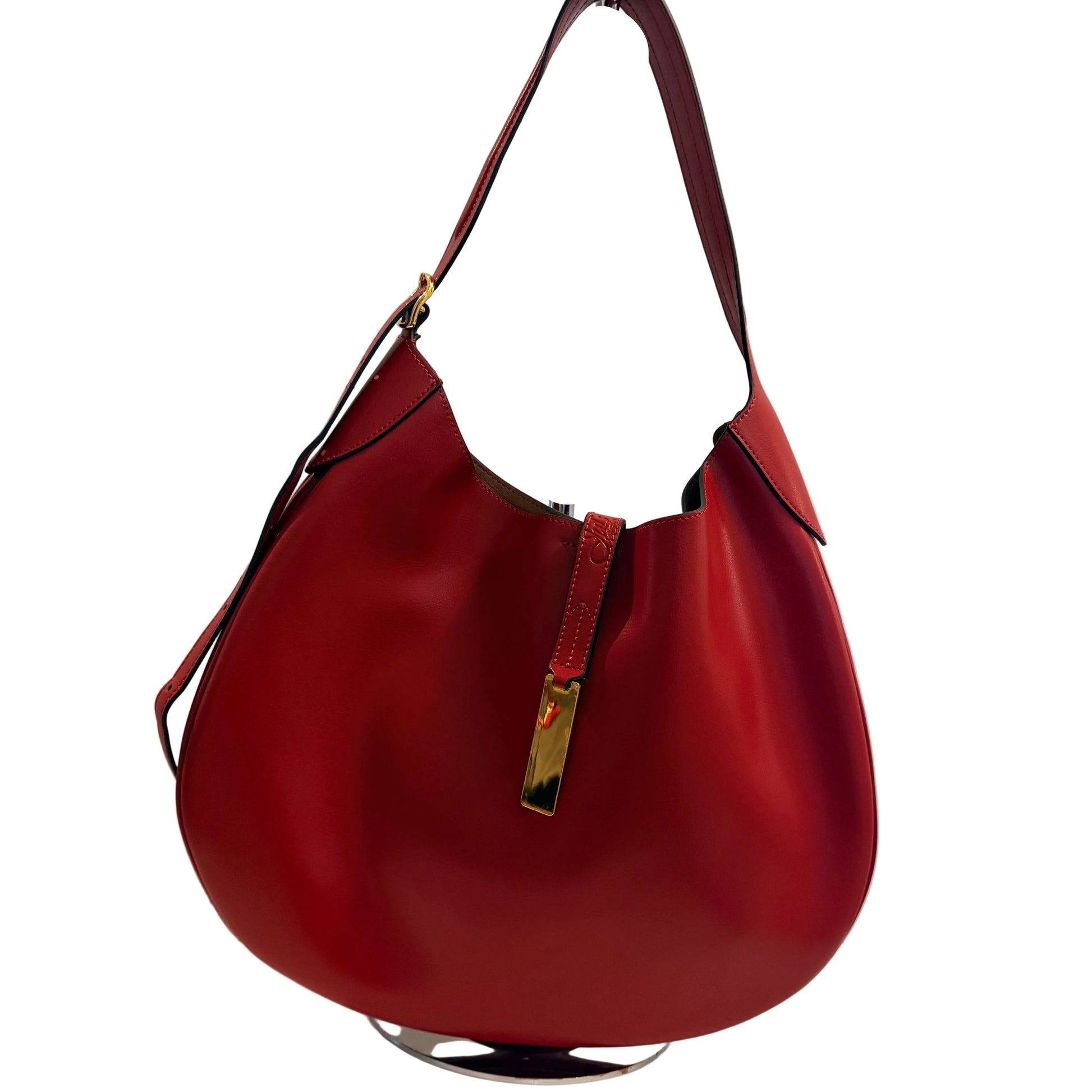 Red handbag with a gold clasp on a white surface against a gray background