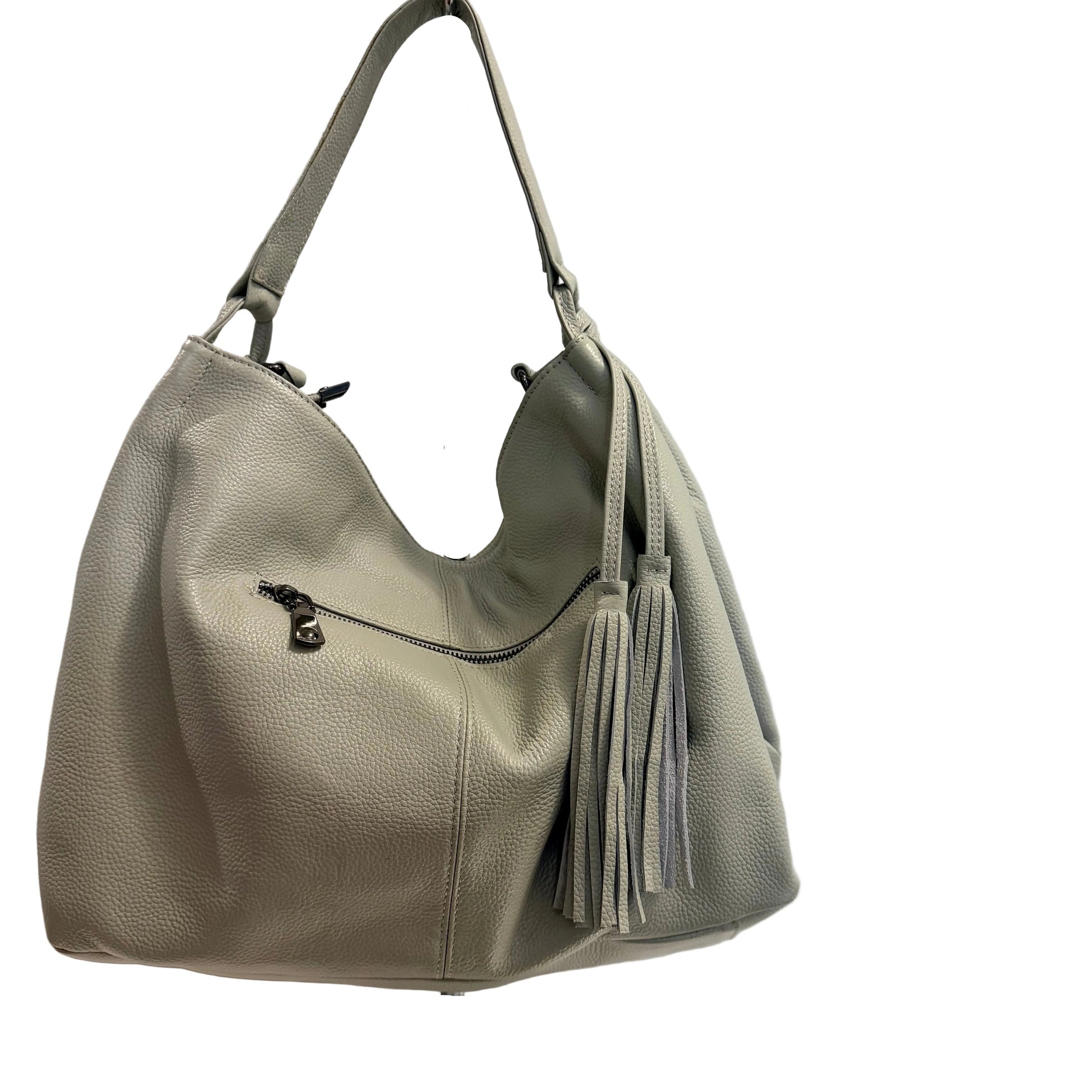Light gray handbag with tassel on a white surface and light gray background