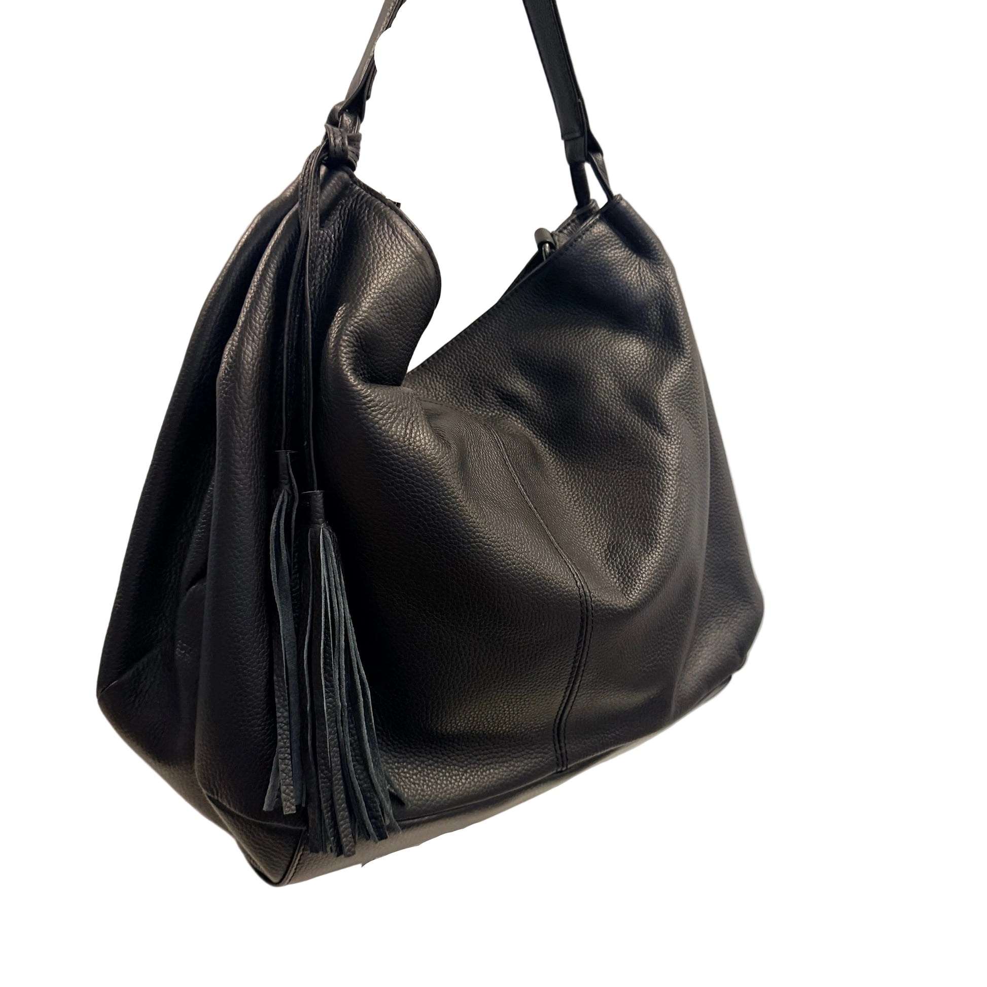 Black leather handbag with a tassel on a white surface against a light gray background
