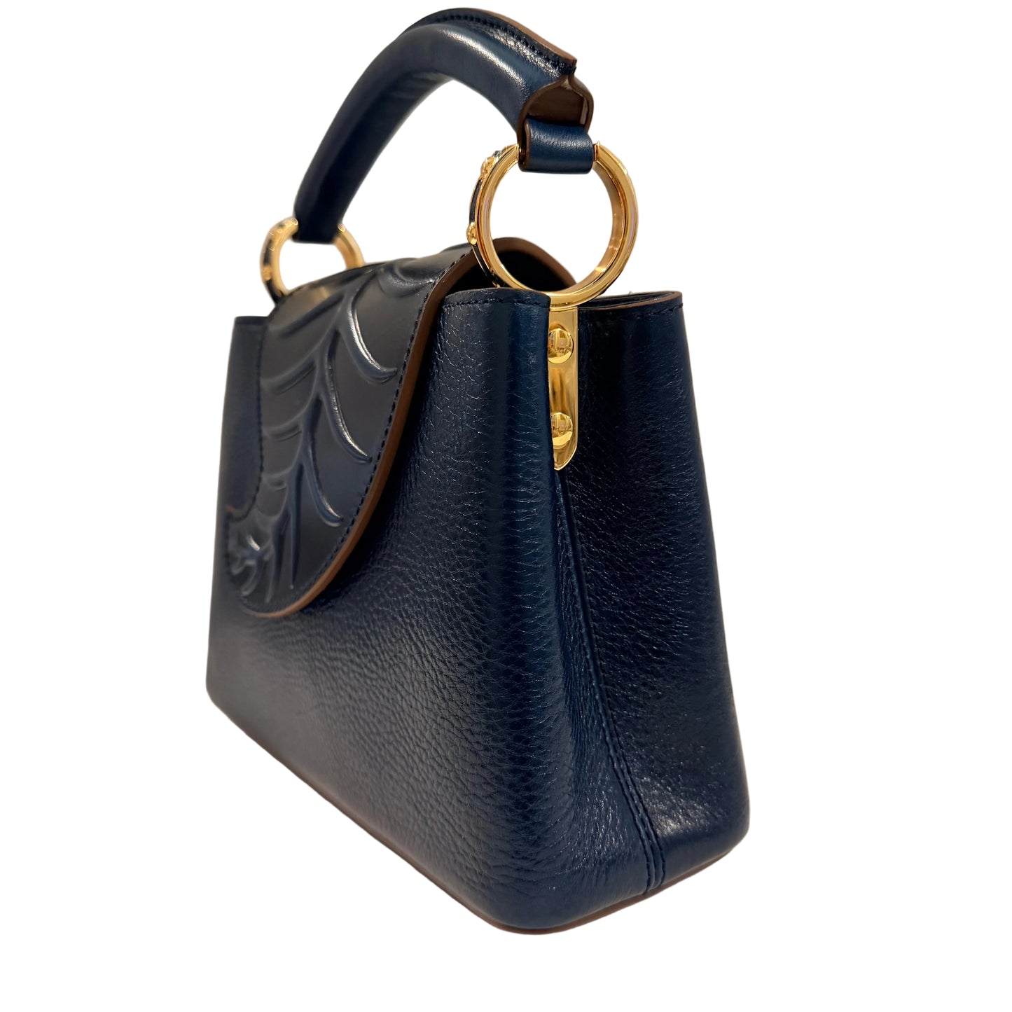 Navy blue handbag with gold ring handle on a neutral background
