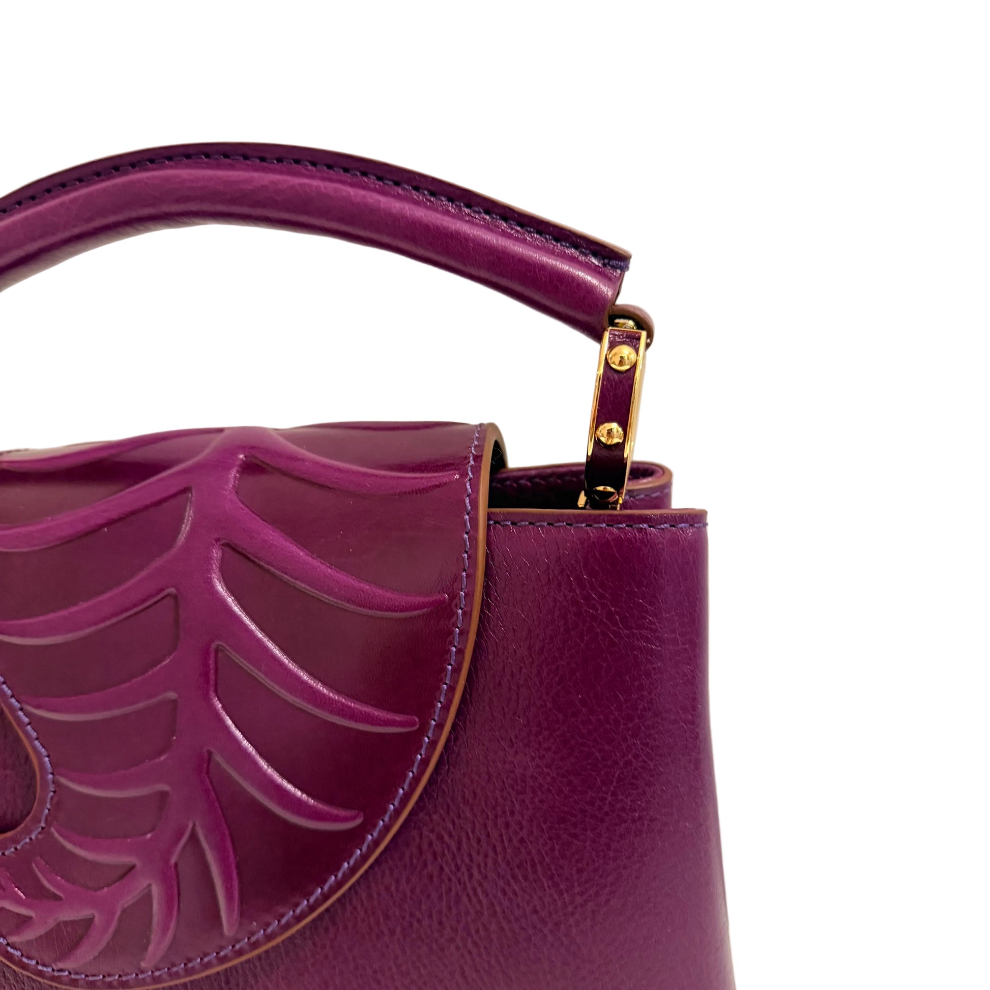 Purple handbag with leaf-like design and gold accents on a light background