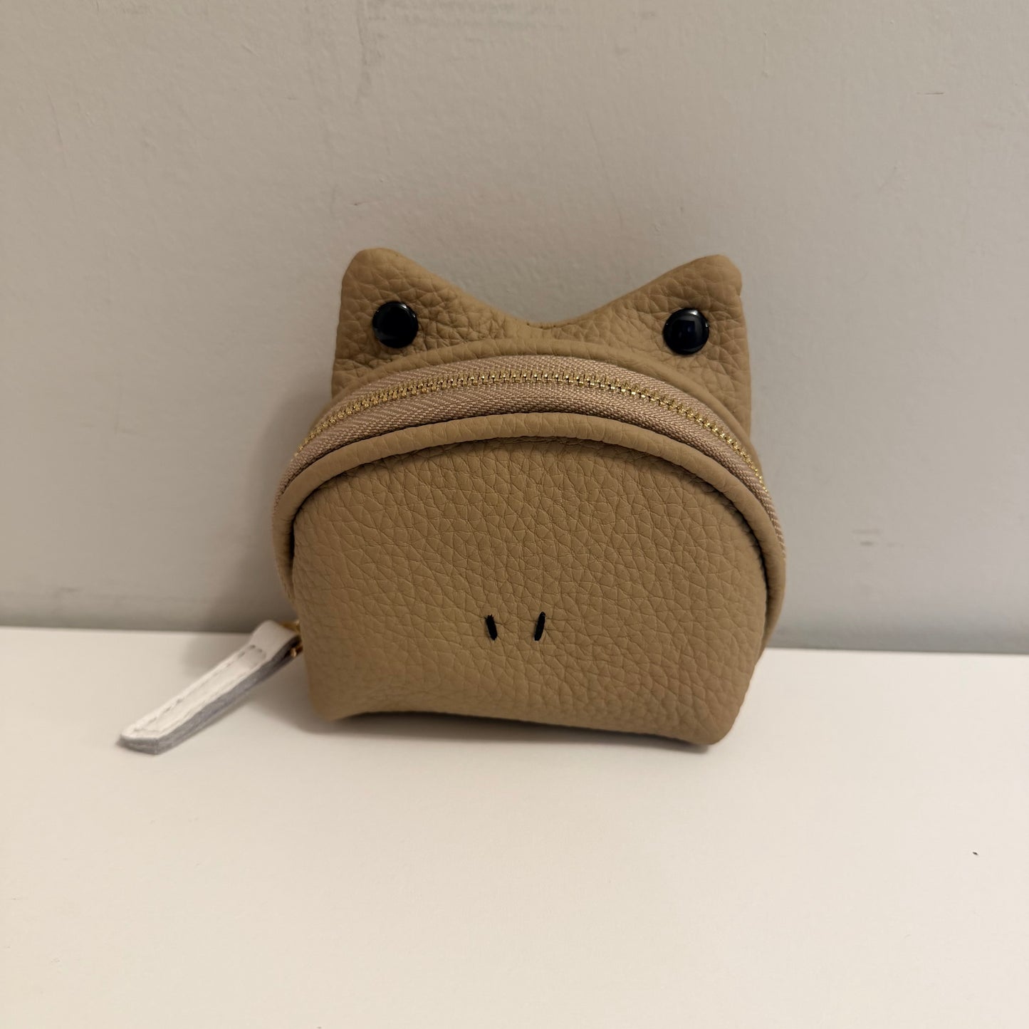 Brown cat-shaped pouch with a zipper on a white surface against a gray background