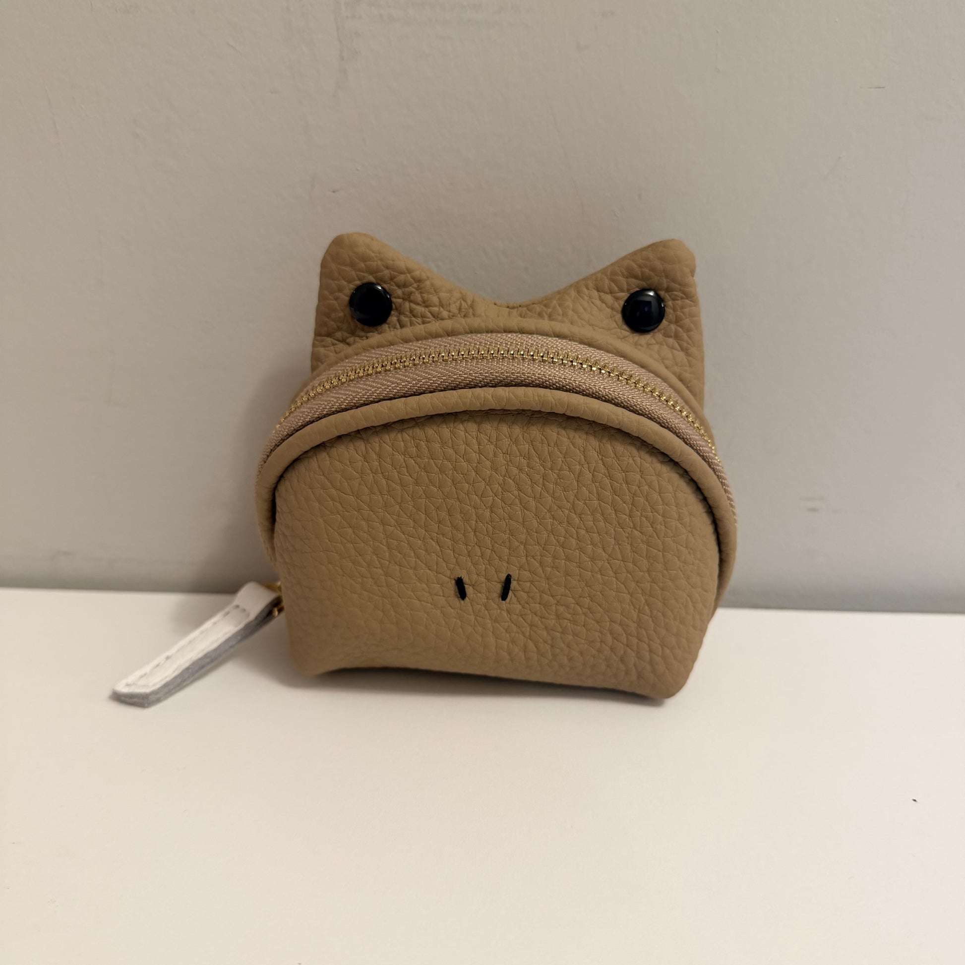 Brown cat-shaped pouch with a zipper on a white surface against a gray background