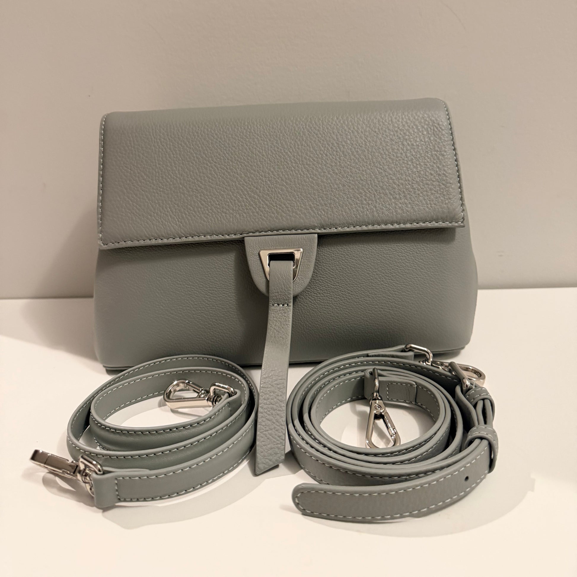 Gray handbag with matching strap on a light beige background