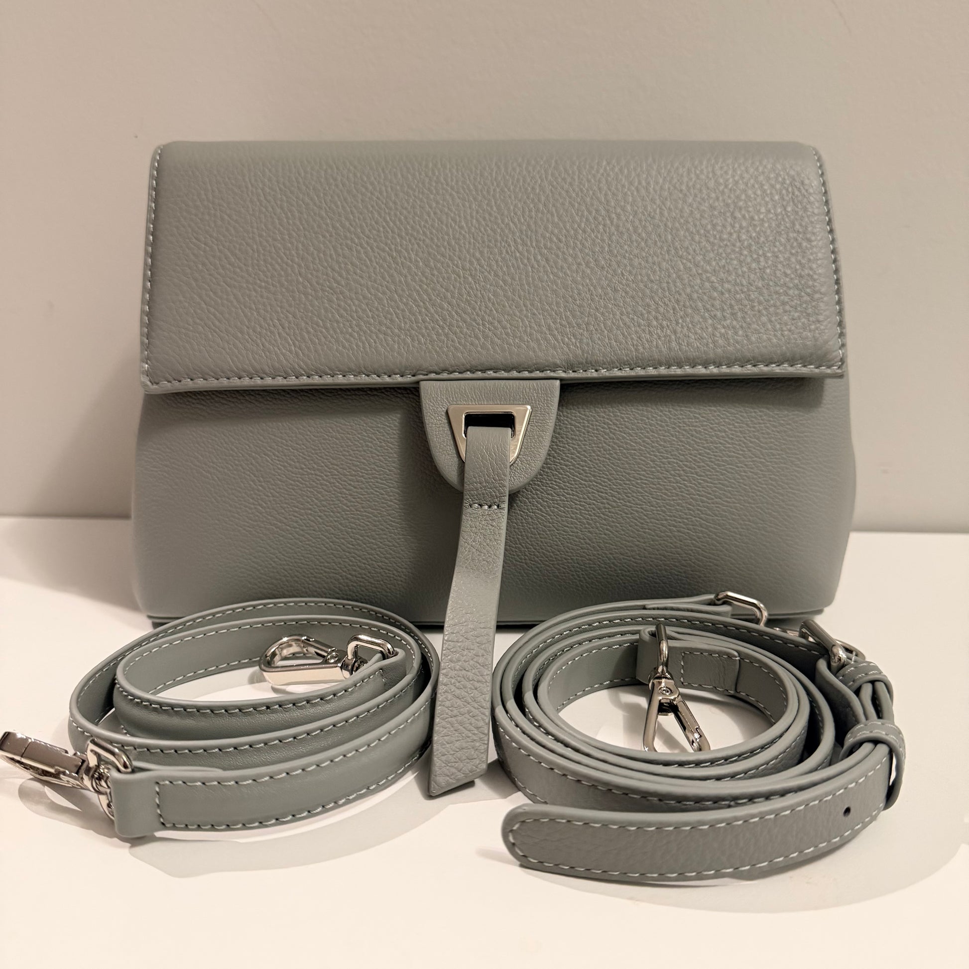 Gray leather handbag with matching strap on a light background