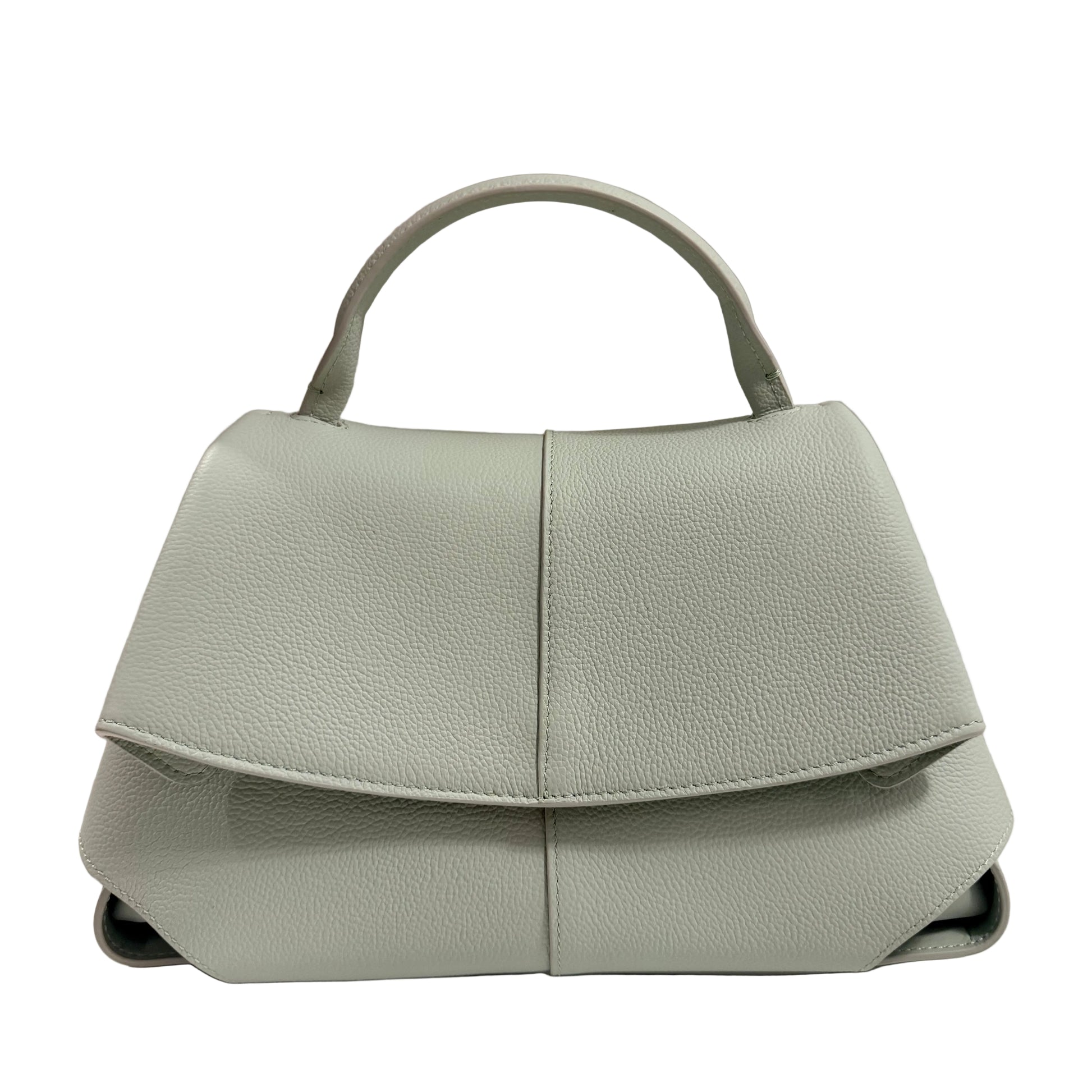 Light green handbag on a white surface with a beige background