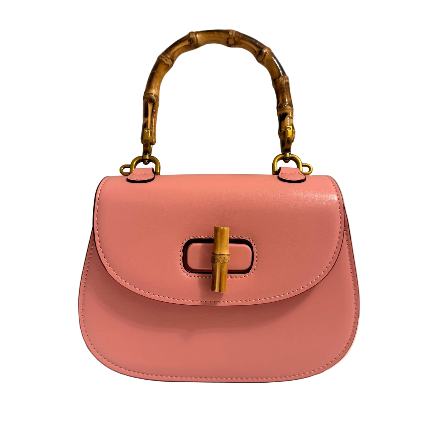 Pink handbag with gold bamboo handle and hardware on a neutral background
