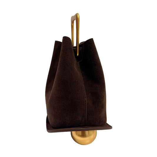 Brown handbag with gold handle and base on a white surface with gray background