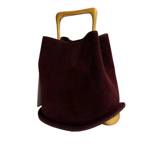 Brown handbag with a gold handle on a light surface
