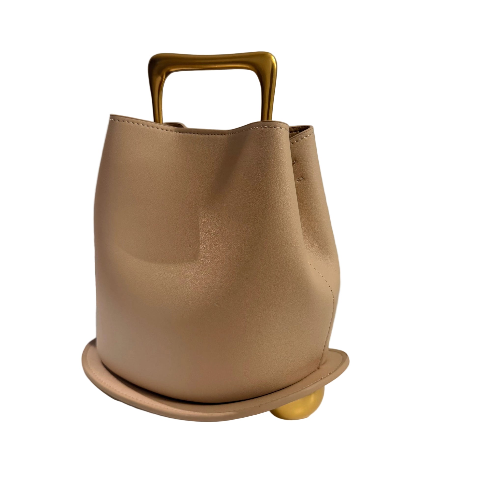 Beige handbag with gold handle on a light surface with a gray background