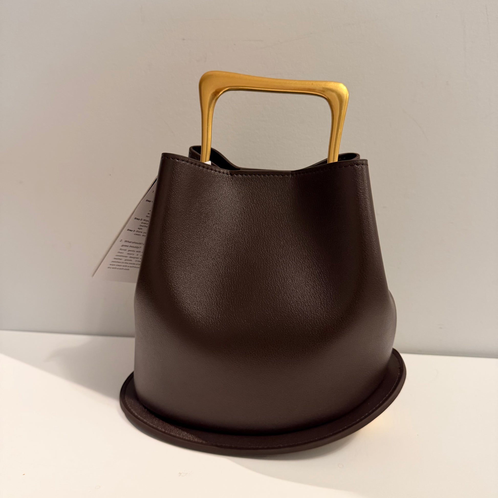 Brown leather bucket with a wooden handle on a light gray background