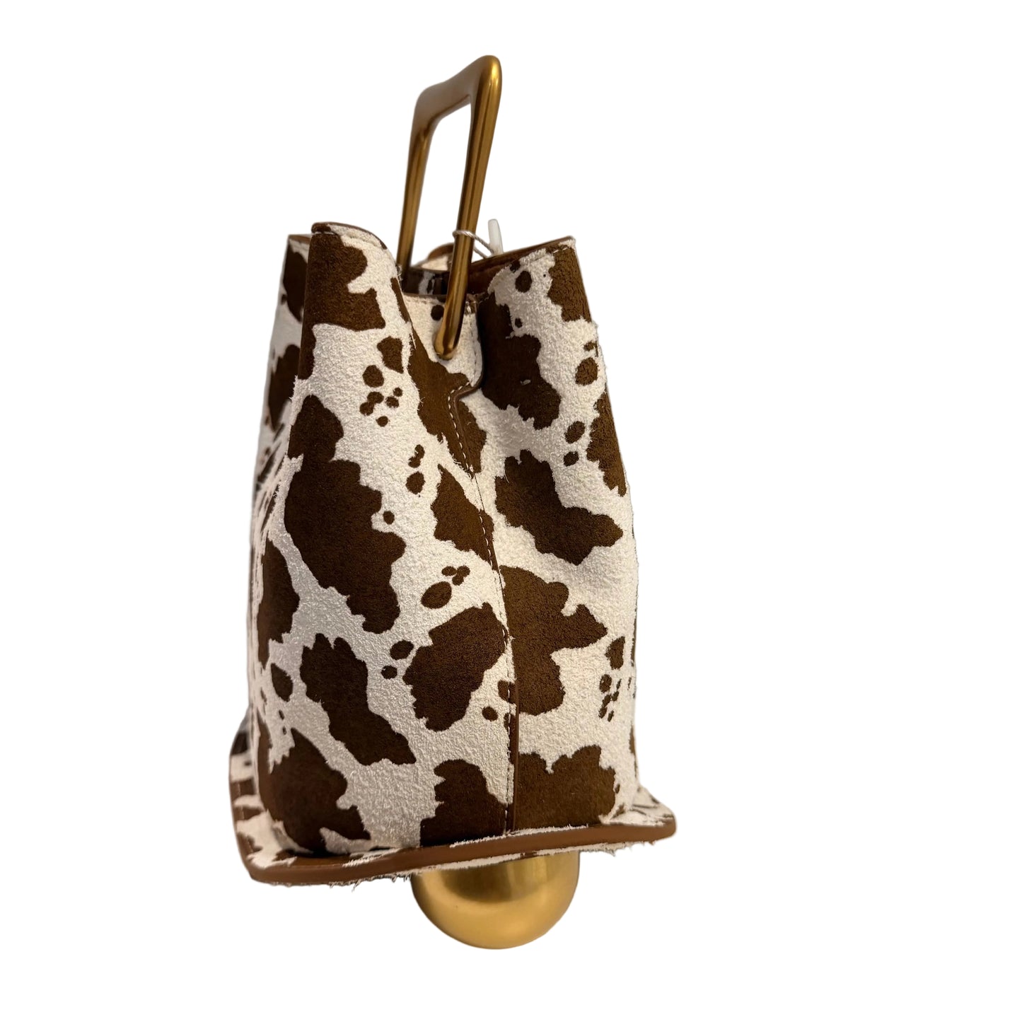 Cow print handbag with gold handle and base on a white surface