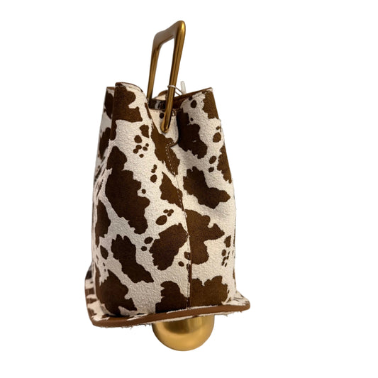 Cow print handbag with gold handle and base on a white surface