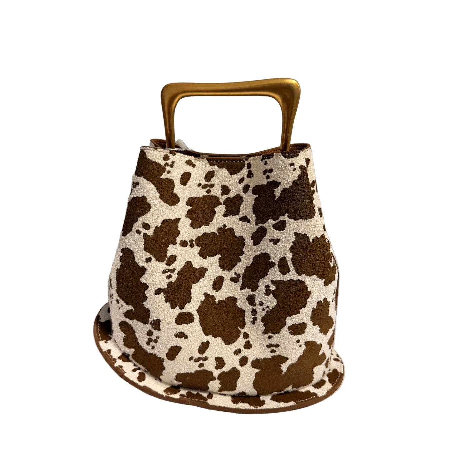 Cow print handbag with a gold handle on a white surface.