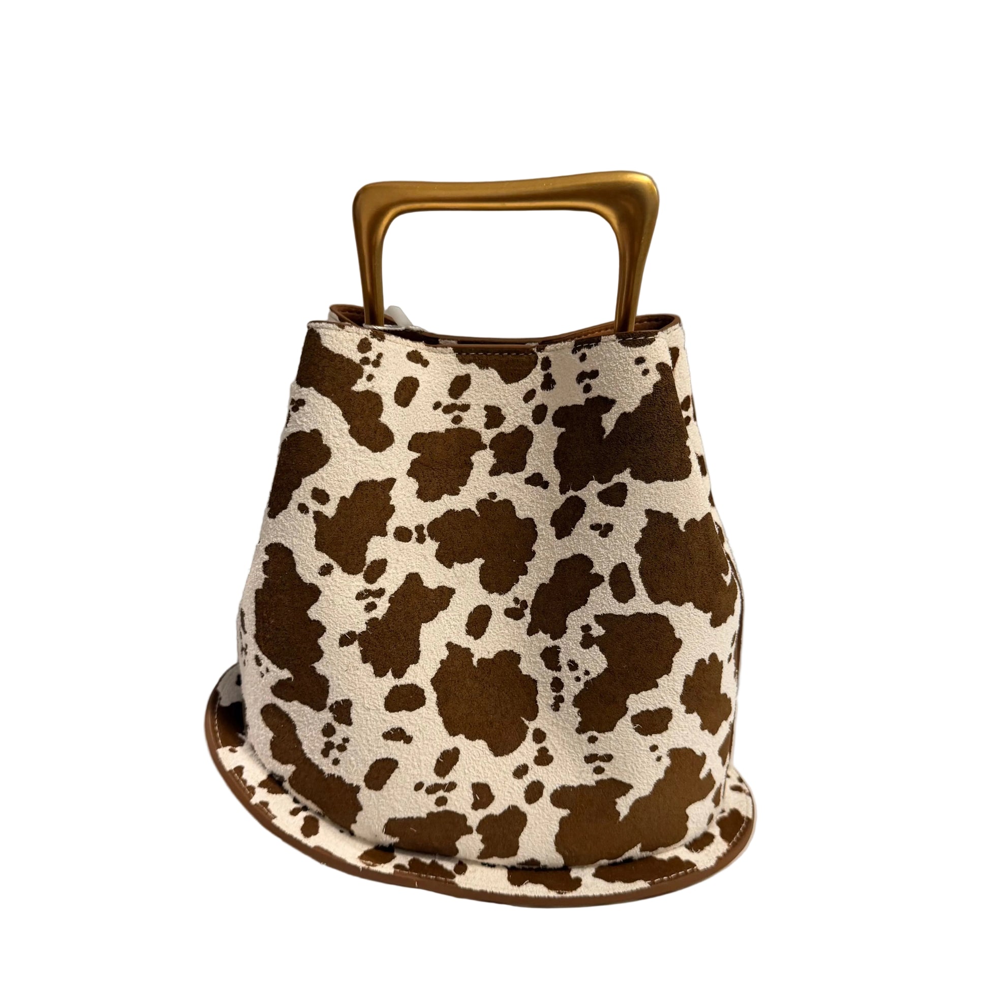 Cow print handbag with a gold handle on a white surface.