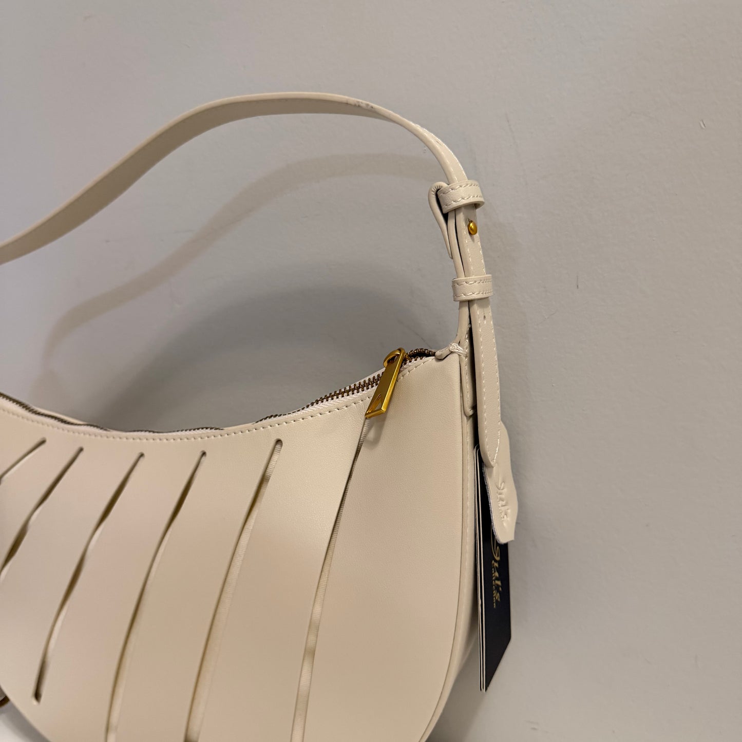Beige handbag with a gold zipper on a light gray background
