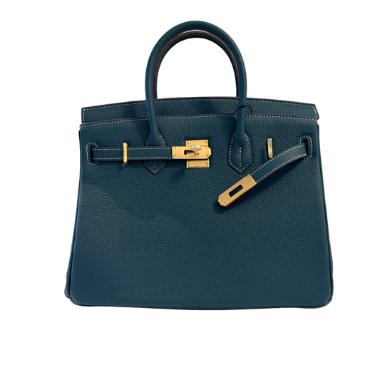 Blue handbag with gold hardware on a neutral background
