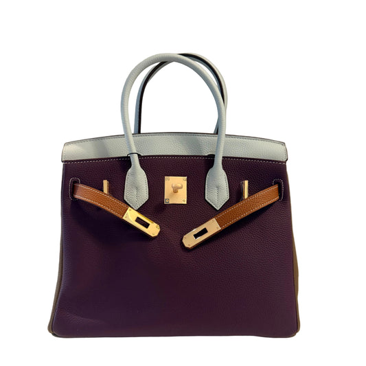 Luxury handbag with gold hardware on a neutral background