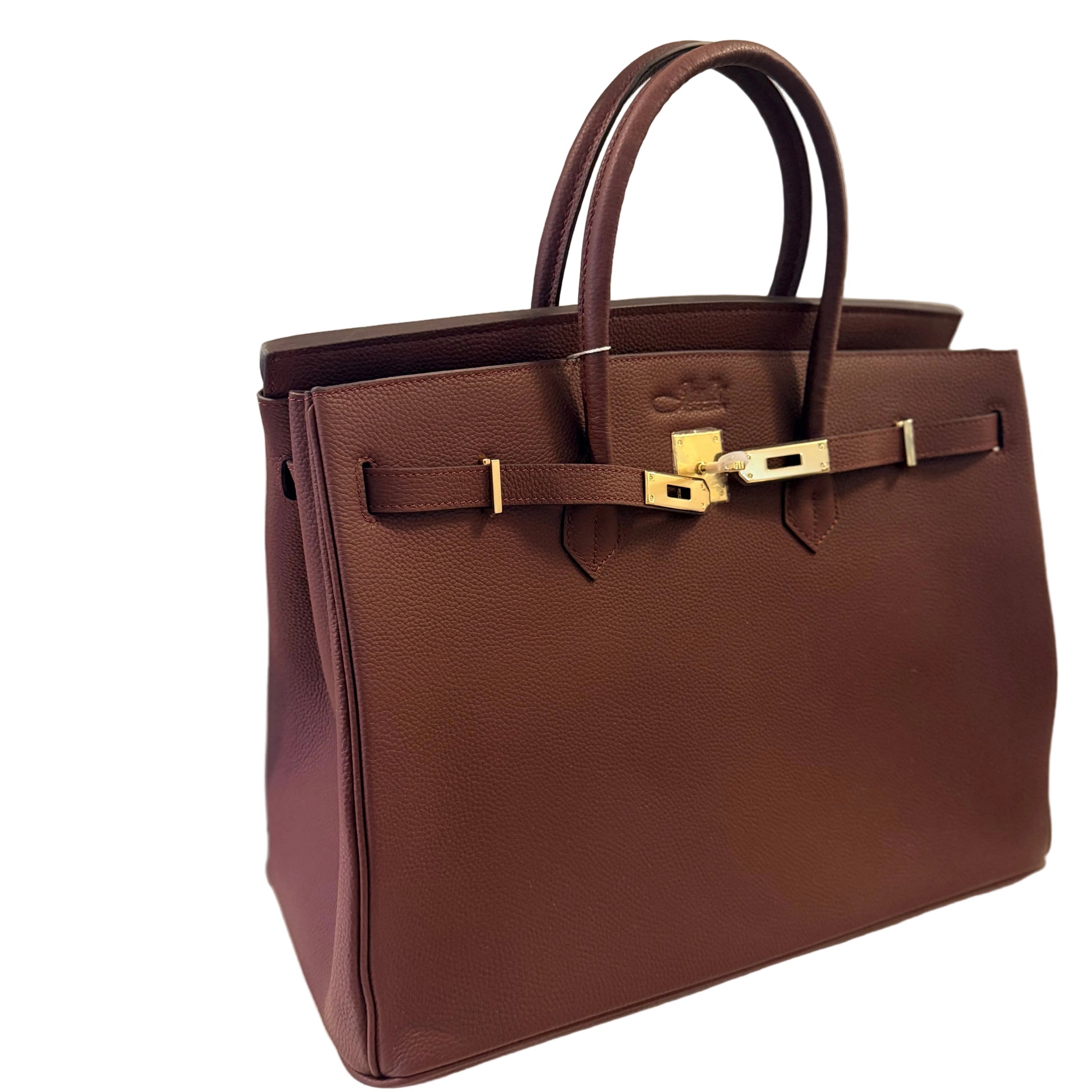 Brown handbag with gold hardware on a light gray background