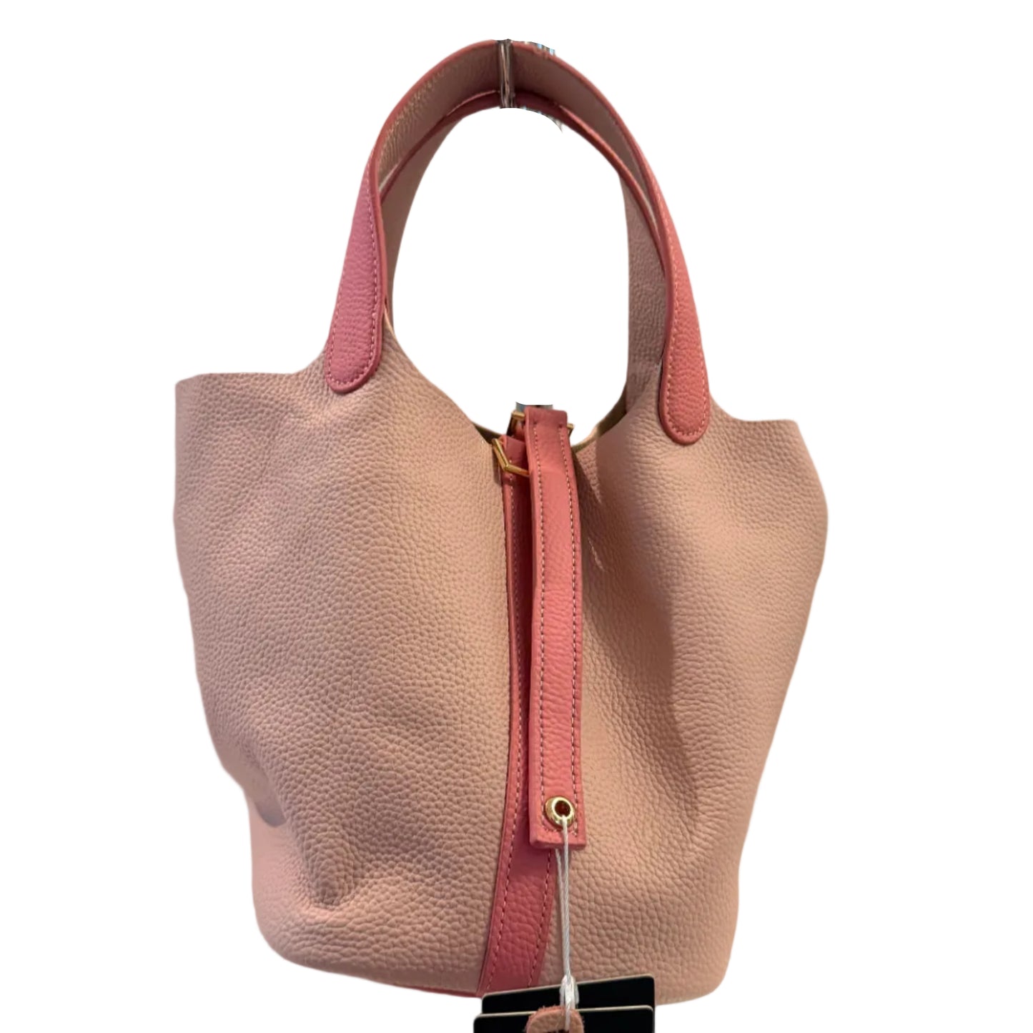 Pink handbag held by a hand against a neutral background