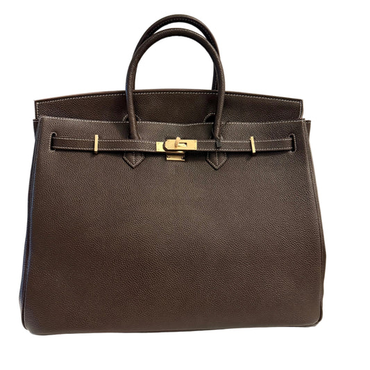 Brown leather handbag with gold hardware on a light gray background