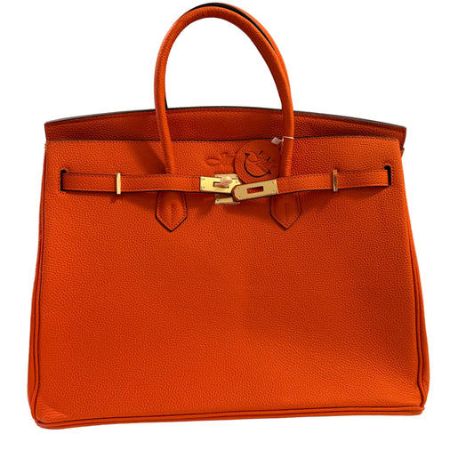Orange leather handbag with gold hardware on a neutral background