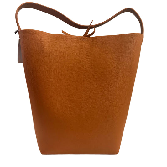 Brown leather tote bag on a white surface with a neutral background