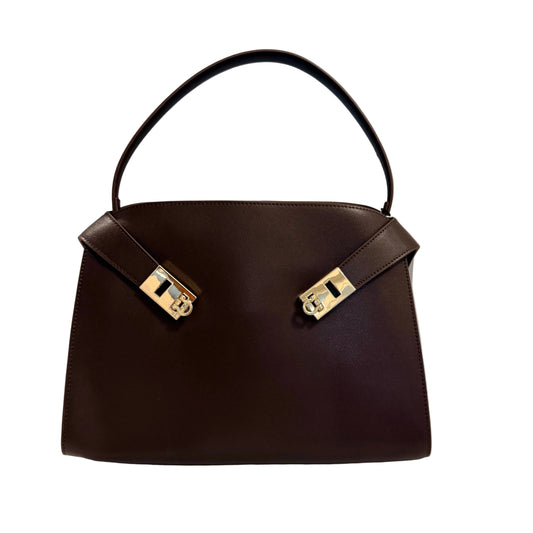 Brown handbag with gold hardware on a white surface and light gray background
