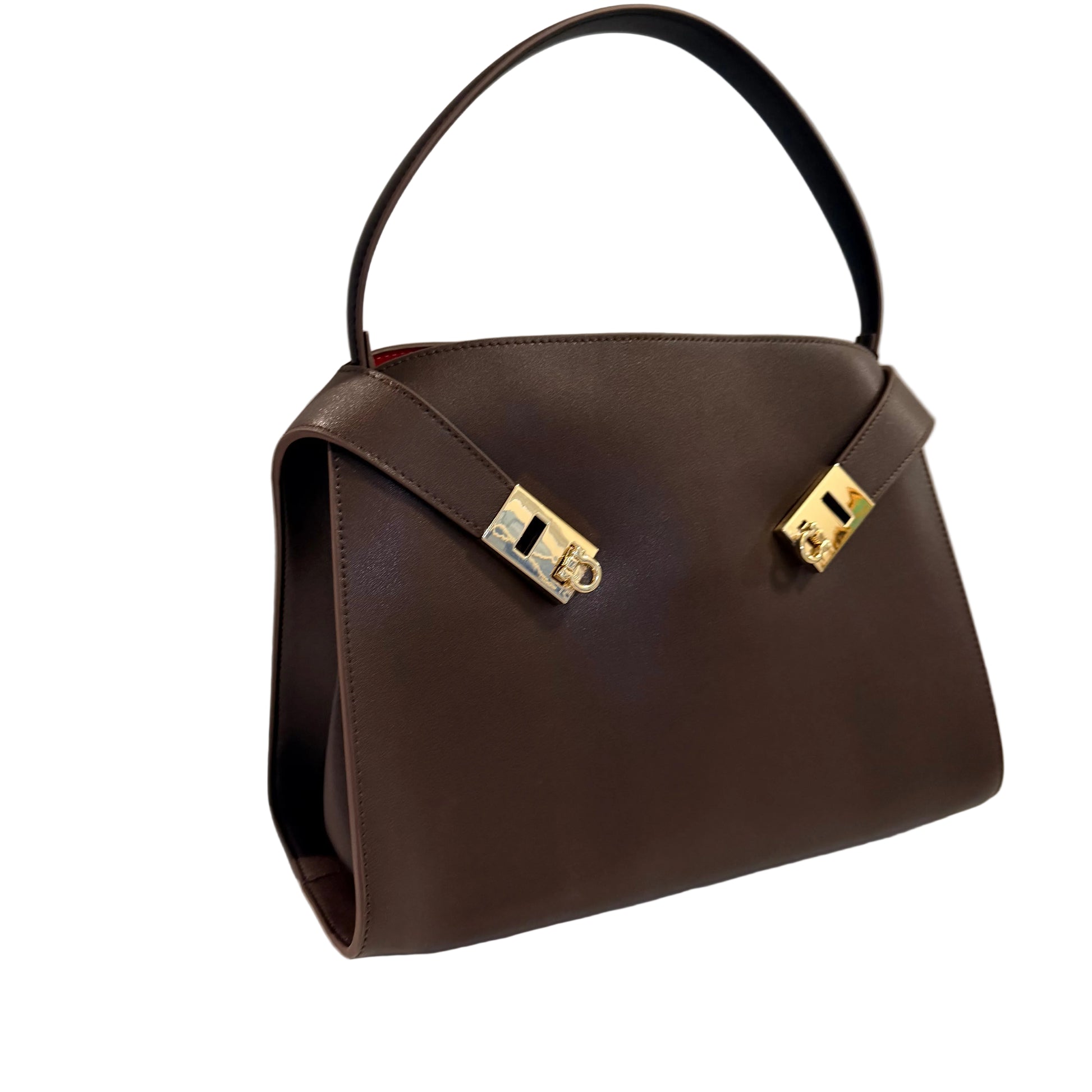 Brown handbag with gold hardware on a white surface