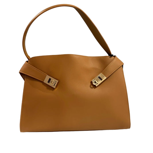 Brown handbag with gold hardware on a light gray background