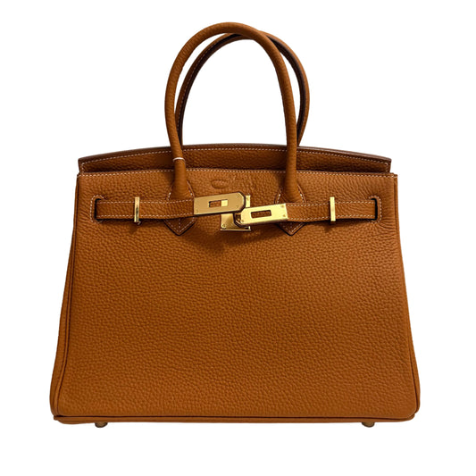 Brown leather handbag with gold hardware on a neutral background