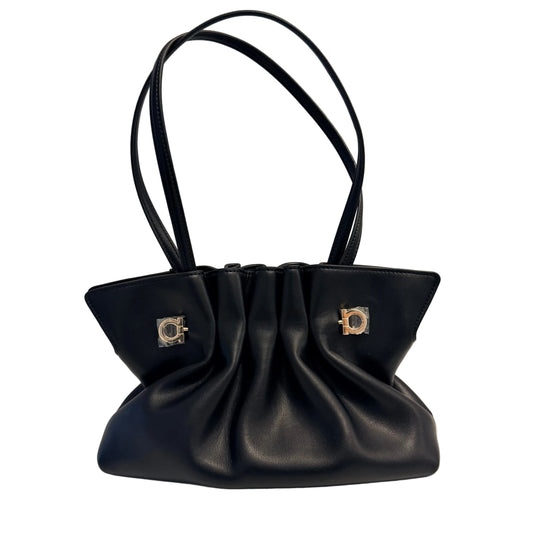 A black leather shoulder bag with a gathered, slouchy silhouette, dual top handles, and two silver-tone metal D-ring hardware details on the front, set against a plain white background.